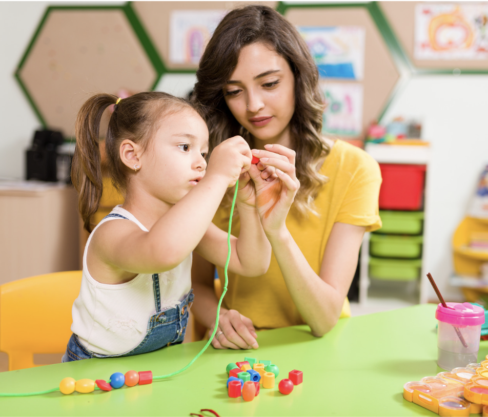 Child stringing beads with adult helping